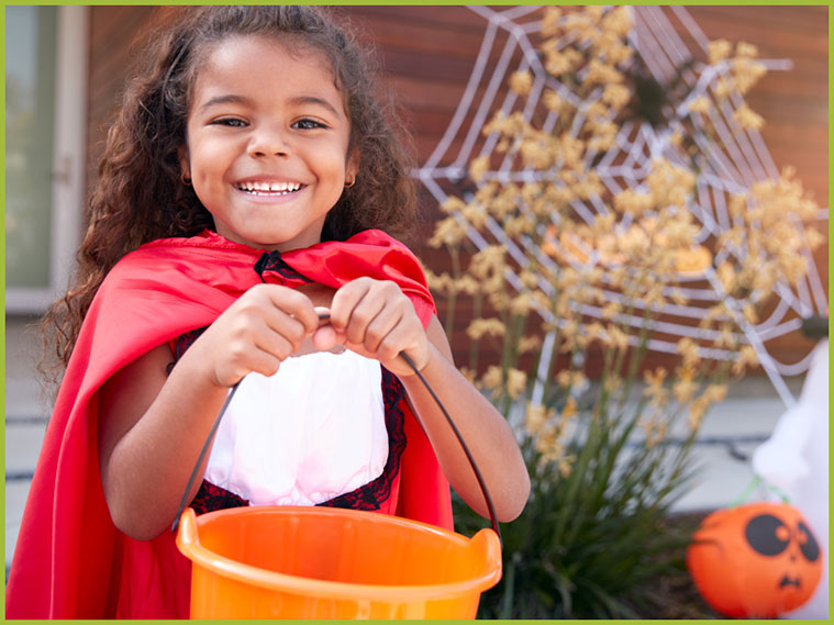 Little girl in costume holding orange pail