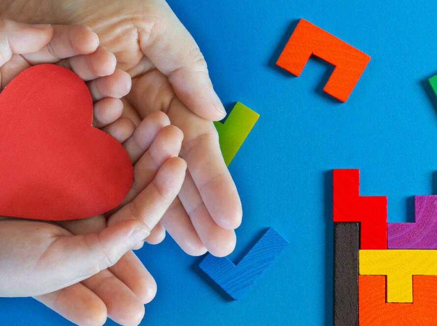 Child's hand holding red heart shape.