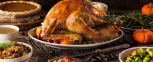 Thanksgiving table showing turkey, mashed potatoes and gravy, vegetables and pumpkin pie