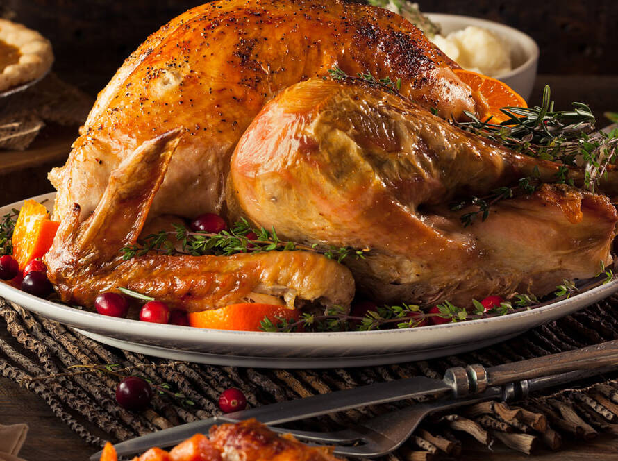 Thanksgiving table showing turkey, mashed potatoes and gravy, vegetables and pumpkin pie